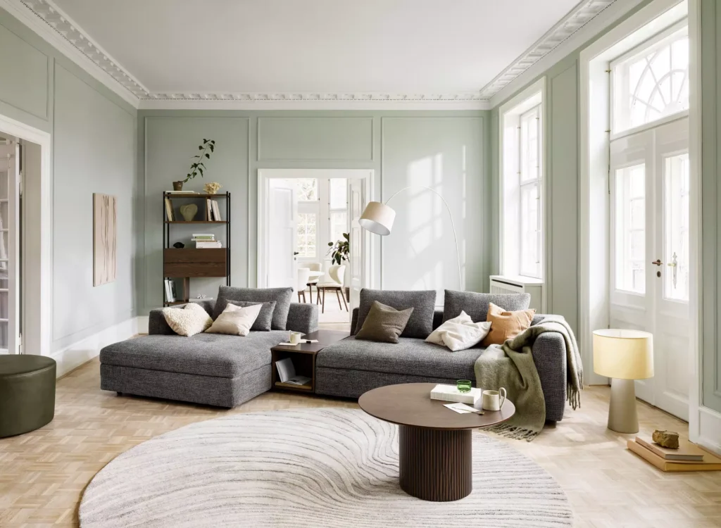 Sofa skandynawska w dużym jasnym salonie, nowoczesna aranżacja z naturalnymi dodatkami i drewnianą podłogą