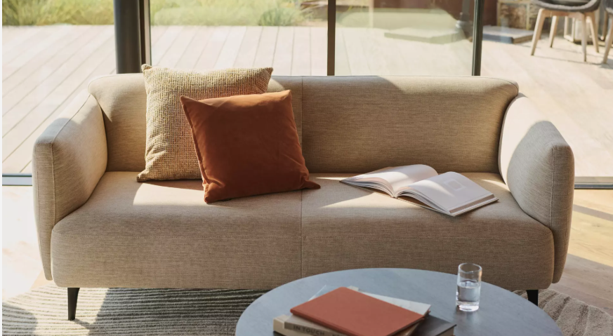 Mała sofa Modena w jasnej tkaninie prezentująca ponadczasowy duński design w nowoczesnym salonie