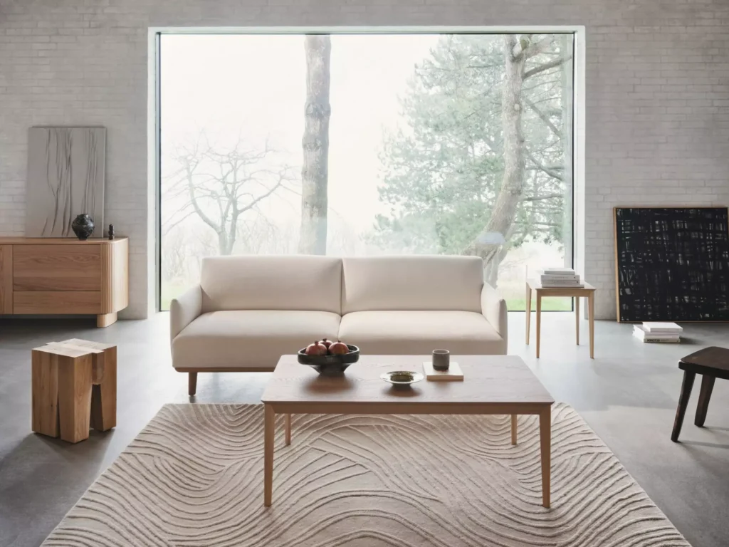 Sofa Aarhus BoConcept z litego drewna i stolik kawowy Aarhus w jasnym salonie inspirowanym duńskim designem.