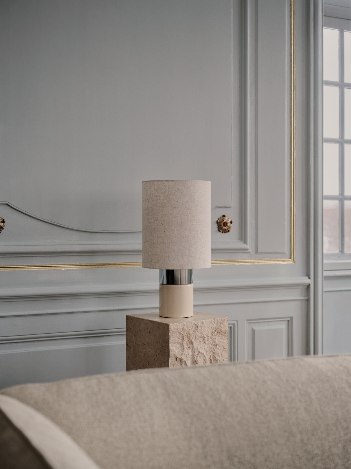 Lampa stołowa z tkaninowym kloszem, ustawiona w eleganckim salonie BoConcept