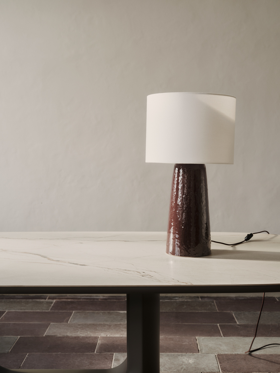 Lampa stołowa BoConcept z ciemną ceramiczną podstawą i jasnym tkaninowym kloszem