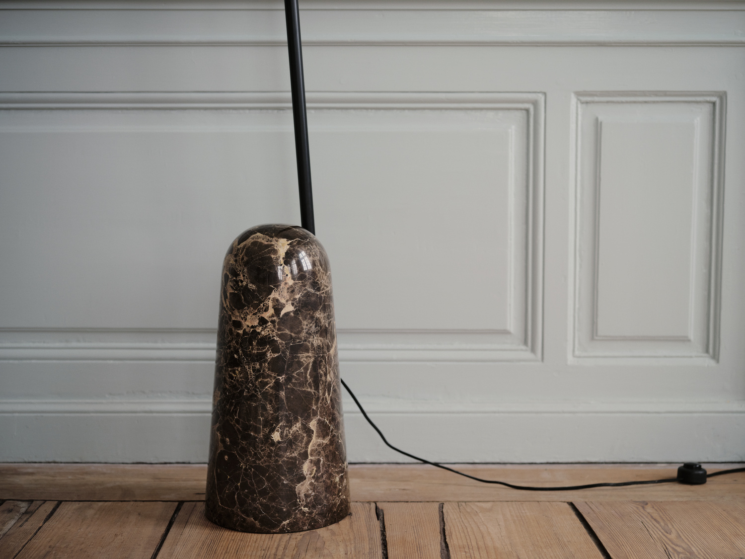 Zbliżenie na ciemną marmurową podstawę lampy podłogowej BoConcept